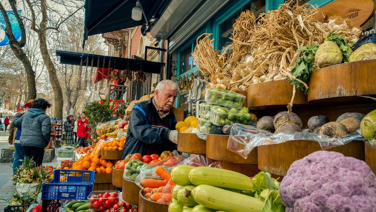 Vibrant street market scene with a man selecting fresh vegetables from a display.
